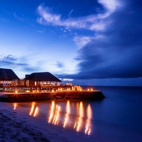 Romantic restaurant on the beach, beautiful night seascape, luxury resort on Maldives, dark blue sky, summer vacation concept